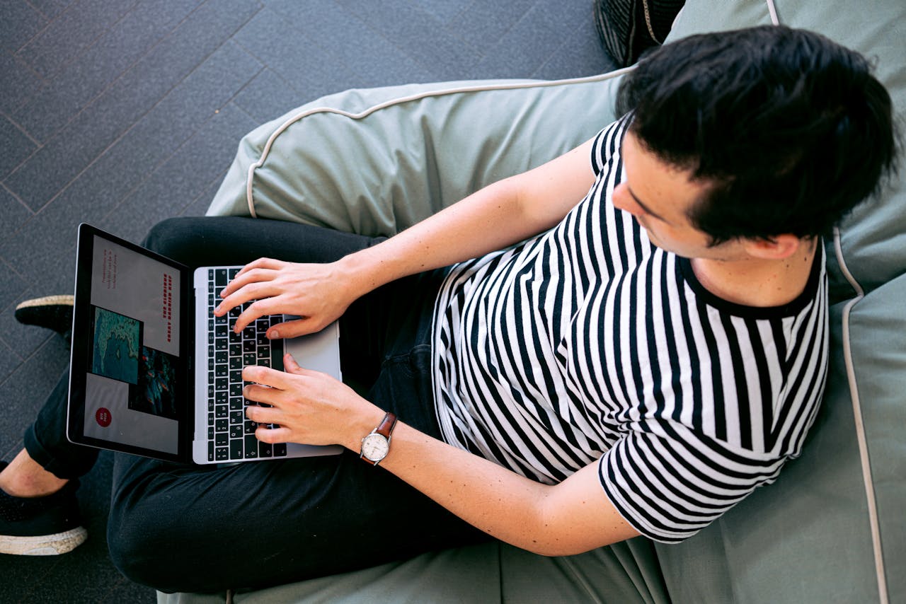 heros-img A man in a striped shirt using a laptop on a bean bag, embodying relaxed productivity.